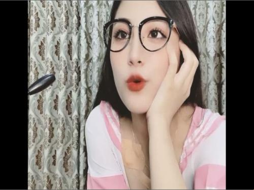 Dia memakai kacamata dan memamerkan payudaranya yang besar